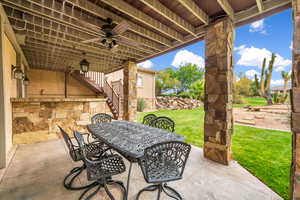 View of patio featuring stairs, outdoor dining area, and a ceiling fan