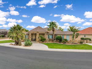 View of front of home featuring stone siding, a tile roof, a front lawn, curved driveway, and stucco siding