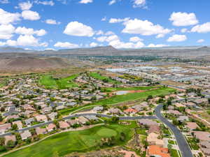 Aerial view of residential area featuring a mountainous background and a golf club
