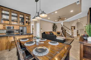 Dining space featuring a raised ceiling, recessed lighting, arched walkways, light tile patterned floors, and ceiling fan