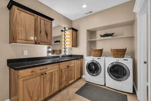 Laundry room with light tile patterned floors, cabinet space, and separate washer and dryer