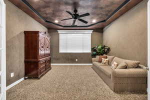 Sitting room with a ceiling fan, carpet flooring, a textured wall, and a raised ceiling
