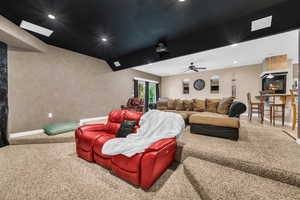 Carpeted cinema room with a large fireplace, lofted ceiling, and recessed lighting