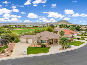 View of front facade with stone siding, driveway, a garage, stucco siding, and a mountain view