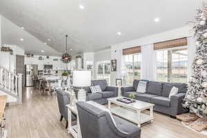 Living room with stairway, light wood-type flooring, recessed lighting, a chandelier, and lofted ceiling