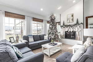 Living room featuring hardwood / wood-style floors, vaulted ceiling, a glass covered fireplace, and recessed lighting