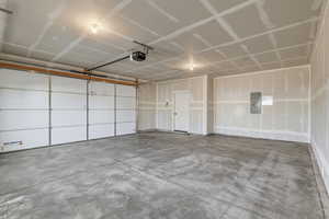 Garage featuring electric panel and a garage door opener