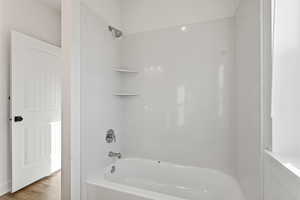 Bathroom with tub / shower combination and wood finished floors