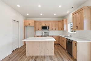 Kitchen featuring light brown cabinetry, recessed lighting, appliances with stainless steel finishes, a center island, and light wood-type flooring