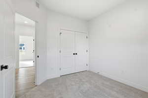 Unfurnished bedroom featuring light colored carpet and a closet
