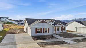 Modern inspired farmhouse featuring board and batten siding, concrete driveway, a shingled roof, and a mountain view