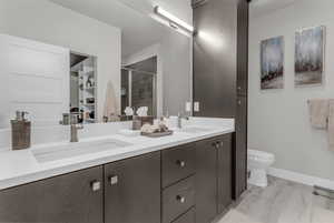 Bathroom featuring a stall shower, double vanity, and a walk in closet