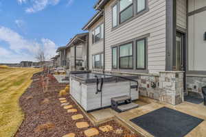View of side of property with a sunroom, a patio, and a hot tub
