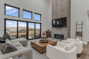 Living room featuring a stone fireplace, a high ceiling, wood finished floors, and a mountain view