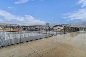View of tennis court with a residential view and basketball hoop