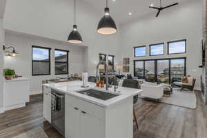 Kitchen with decorative light fixtures, white cabinetry, modern cabinets, open floor plan, and dark wood-style flooring