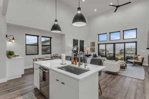 Kitchen with white cabinetry, pendant lighting, a breakfast bar, open floor plan, and dark wood-type flooring