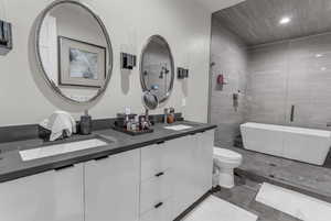Full bathroom featuring double vanity, a freestanding tub, a stall shower, and recessed lighting