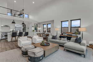 Living area featuring wood finished floors, a towering ceiling, and recessed lighting