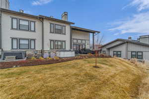 Back of house featuring a lawn, a chimney, a hot tub, and board and batten siding