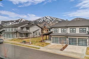 View of front of home with driveway, a garage, a residential view, a mountain view, and a shingled roof