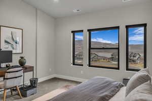 Bedroom featuring a desk, light carpet, and a mountain view