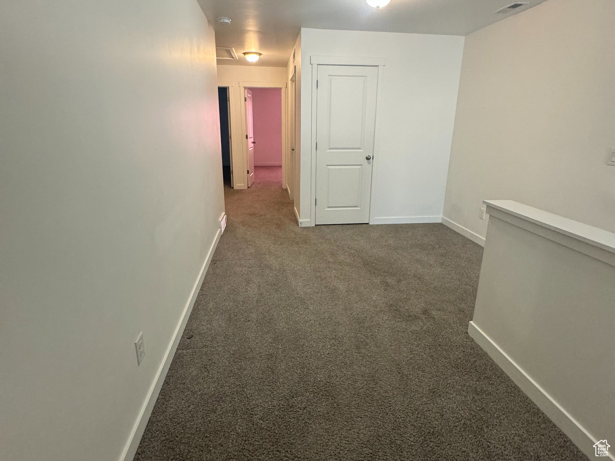 Corridor with dark carpet and baseboards