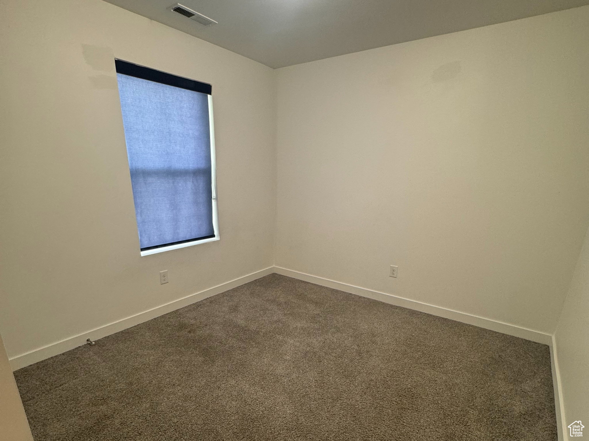 Carpeted spare room featuring baseboards