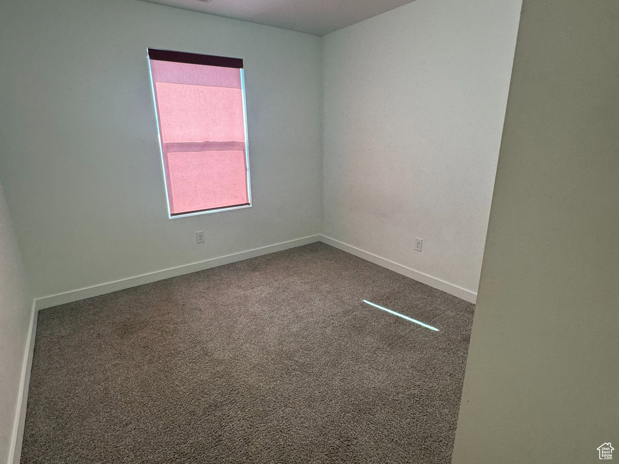 Spare room featuring carpet flooring and baseboards