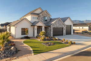 View of front of property featuring stucco siding, stone siding, concrete driveway, a garage, and a mountain view