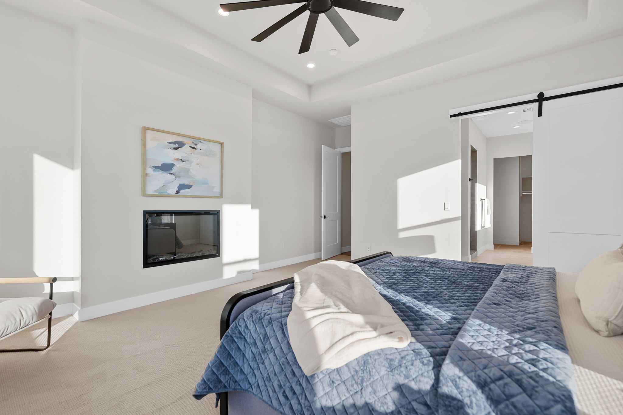 Bedroom featuring a barn door, light colored carpet, ceiling fan, a glass covered fireplace, and recessed lighting