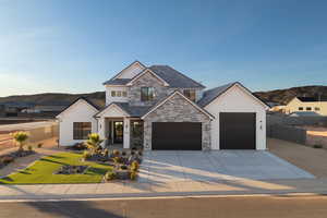View of front facade featuring stucco siding, driveway, stone siding, and a garage
