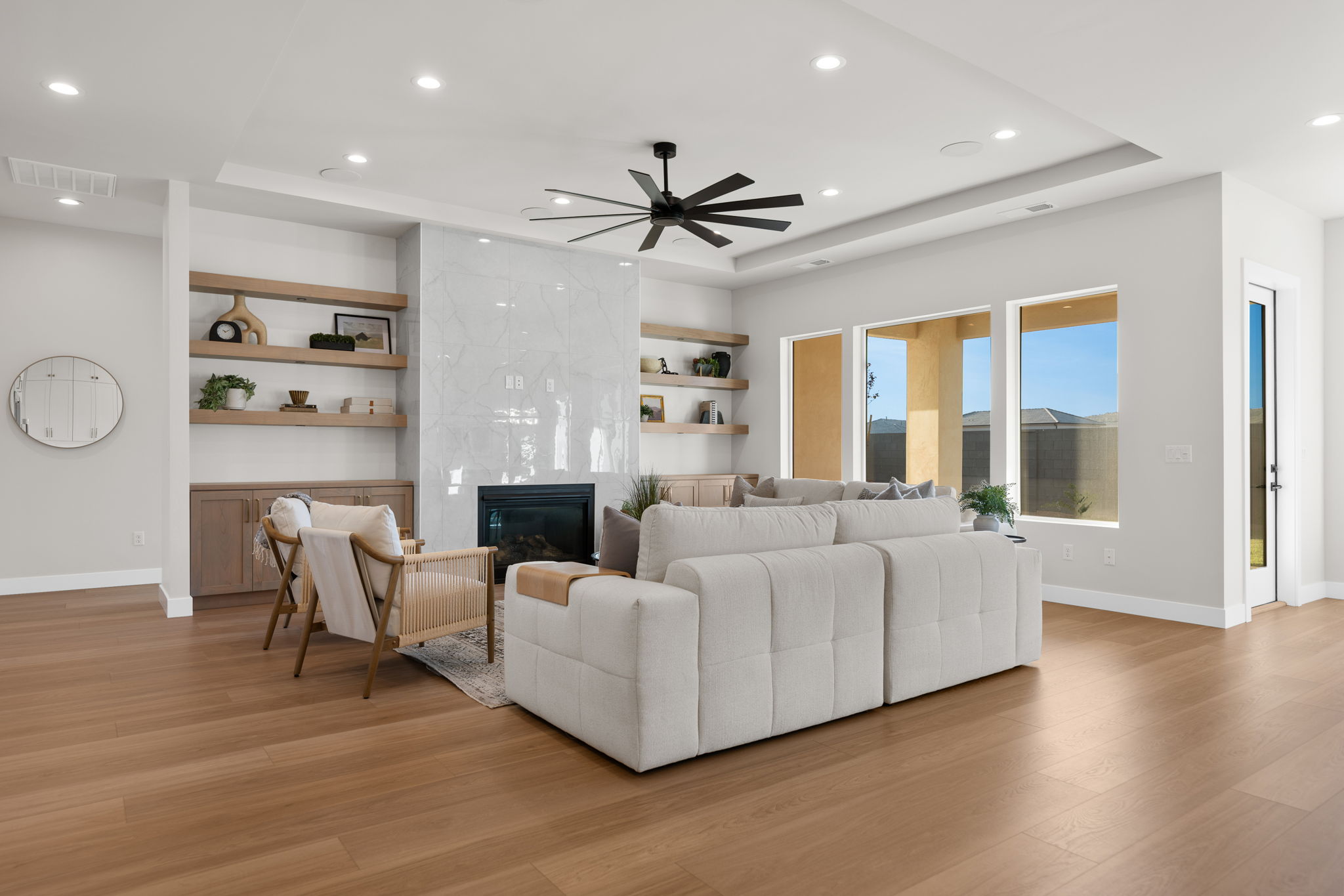 Living room featuring a premium fireplace, recessed lighting, light wood-style flooring, built in shelves, and a raised ceiling