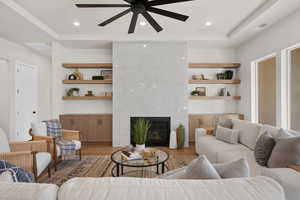 Living room with a high end fireplace, light wood-type flooring, built in features, and recessed lighting