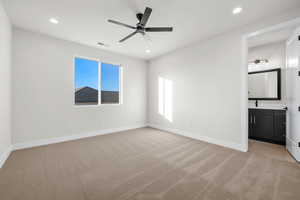 Unfurnished bedroom featuring light carpet, ceiling fan, recessed lighting, and ensuite bathroom