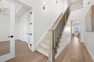 Stairway with wood finished floors, recessed lighting, a towering ceiling, and a chandelier