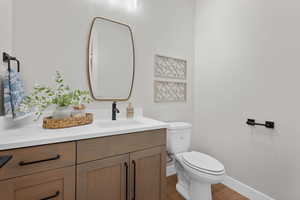 Half bath with vanity and wood finished floors