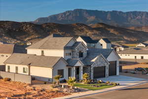 View of front facade featuring concrete driveway, a mountain view, stone siding, and stucco siding