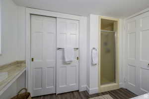Full bathroom featuring a stall shower, dark wood finished floors, and a closet