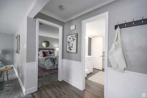 Bedroom with dark wood-style flooring, crown molding, and connected bathroom