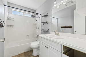 Bathroom featuring bathtub / shower combination, vanity, and stone tile flooring