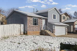 Tri-level home with brick siding, a garage, and concrete driveway