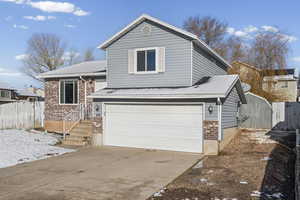 Tri-level home featuring a garage, brick siding, and concrete driveway