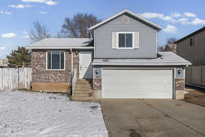 Tri-level home featuring brick siding, an attached garage, and concrete driveway