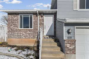 Property entrance featuring brick siding and an attached garage