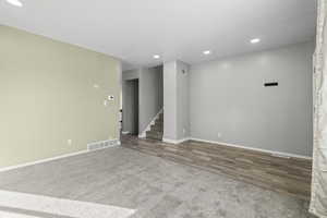 Spare room featuring recessed lighting, stairs, carpet flooring, and wood finished floors