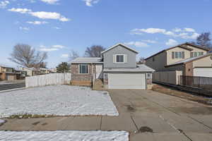 Tri-level home featuring brick siding, driveway, a garage, and a residential view