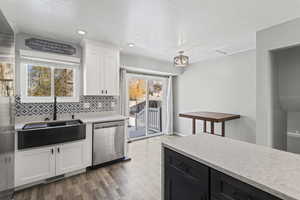 Kitchen with light stone countertops, white cabinets, tasteful backsplash, stainless steel dishwasher, and a textured ceiling