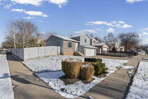 View of front of house with an attached garage, a residential view, concrete driveway, and brick siding