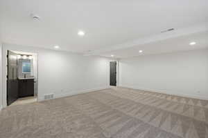 Finished below grade area with recessed lighting and light carpet